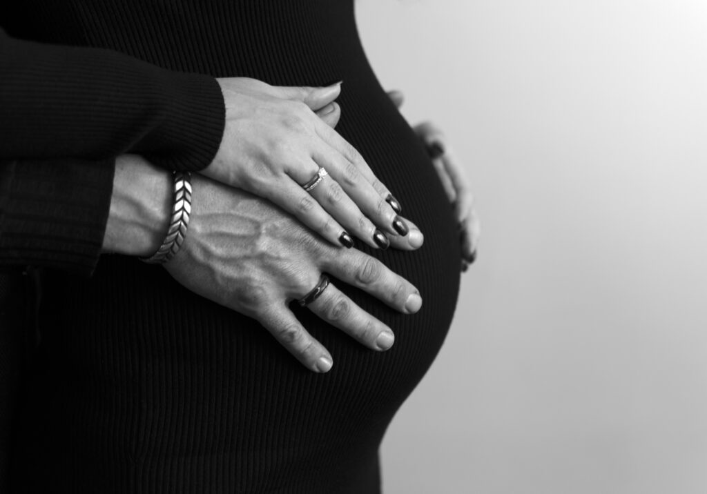 Close‑up of hands gently resting on a pregnant belly during a maternity photo session in New Jersey.