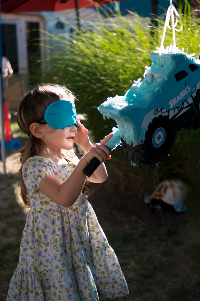 Kids 3 Young girl in a blindfold reaching hit pinatas at an outdoor birthday celebration in NJ.