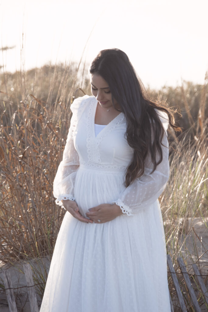 Mom photo Back Natural light portrait of a mother-to-be smiling at the Jersey shore beach near pampas grass.