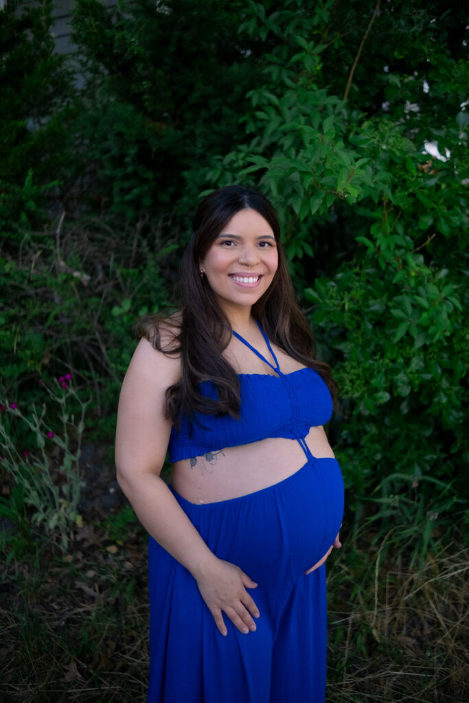 Mother to be 3 Picture of pregnant woman in a flowing blue gown walking along the green bushes at the Jersey Shore.